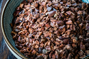 Chocolate Cacao Nibs or Cocoa Nibs in Bowl Ready to Use on Dark Wooden Surface.