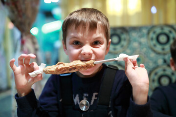 Boy eating kebab on skewer