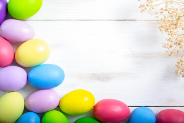 Lots of dyed colorful eggs on a white wooden background with copy space. Easter background.