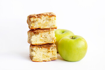 Pieces of homemade organic sponge apple pie near green apples isolated on a white background. Close up of a Dessert Charlotte