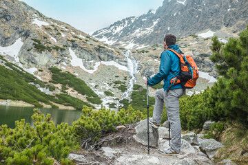 Man hiker, hiking backpacker traveler camper walking on the top of mountain in autumn sunny day under sun light. Beautiful mountain landscape view.