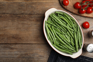 Flat lay composition with raw green beans on wooden table. Space for text
