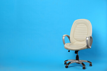 Comfortable office chair on light blue background, space for text