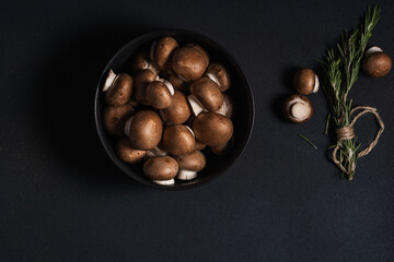 Bowl of raw mushrooms and bunch of fresh rosemary, top view