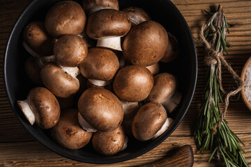 Bowl of mushrooms and bunch of fresh rosemary, top view