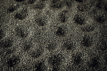 Surface of fine black sand with may craters