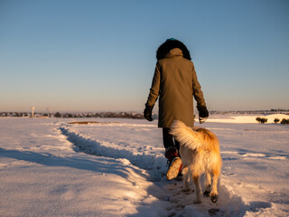 WOMAN WALKING WITH HER DOG IN THE SNOW