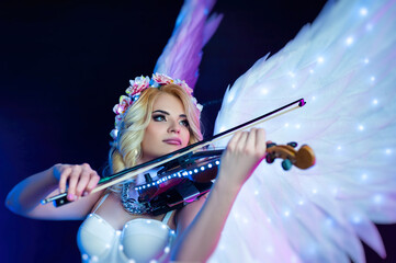 women with angel wings playing violin in neon light