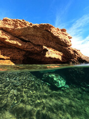 Fototapeta na wymiar Underwater split photo from rocky sea cave formation in calm sea beach of Avlaki, Porto Rafti, Mesogeia, Attica, Greece