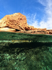 Split underwater photo of tropical exotic Caribbean emerald calm sea rocky bay