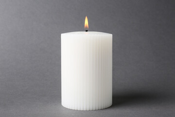 Obraz na płótnie Canvas Stylish white burning candle on grey background