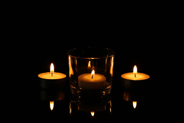 Burning small wax candles in darkness. Funeral symbol