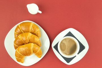 Croissants on a white plate and coffee with milk