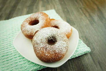 Donuts sprinkled with powdered sugar on a plate