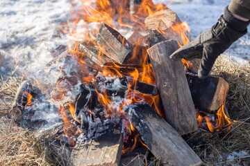 man puts wood to a winter bonfire 