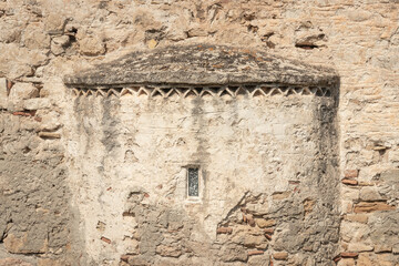 peeling plastered stone wall of orthodox church Ekklisia Agios Ioannis with small window in Greece