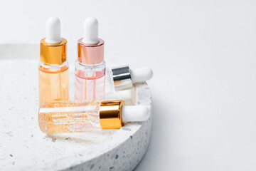 Skin care essence glass bottles on marble cosmetic tray on light background. Vitamins for skin....