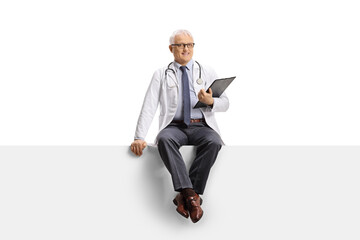 Full length portrait of a mature doctor sitting on a blank panel and looking at camera