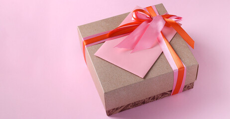 Gift box and envelope with bright ribbon on a pink background. Concept for Valentines Day, Mothers Day or Birthday. With place for text.