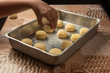 Cheese bread from Brazil, frozen cheese bread being placed in the baking pan, selective focus.