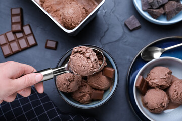 Woman putting chocolate ice cream into bowl at table with dessert, top view