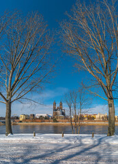 Magdeburg historical downtown in Winter with icy trees and snow during sunrise in the morning with warm illumination and blue sky, Germany.