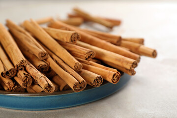 Aromatic cinnamon sticks on grey table, closeup