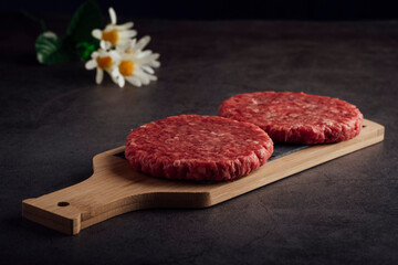 Closeup shot of fresh raw burger patties on a wooden board