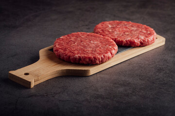 Closeup shot of fresh raw burger patties on a wooden board