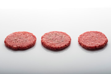 Closeup shot of fresh raw burger patties on a white surface