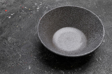 Gray ceramic plate on grey concrete rough background. Empty spotted uneven saucer. Matte dish on stone textured backdrop. Hand made ceramic table setting. Top view