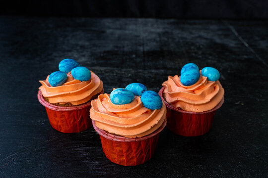 Easter cupcake with whipped orange cream. decorated with blue easter eggs. low key. Copy spece