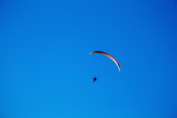 Paragliders in the blue sky practicing aerial acrobatics. Sports in the air