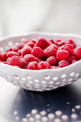 White ceramic colander with fresh ripe raspberries