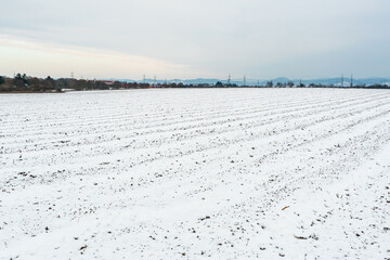 Fototapeta na wymiar Winter landscape with snow-covered agricultural field and hills at skyline