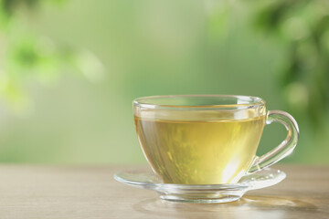 Glass cup of fresh herbal tea on table. Space for text