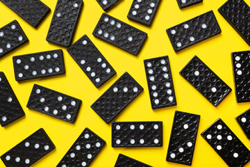 Black domino tiles on yellow background, flat lay