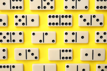 Classic domino tiles on yellow background, flat lay