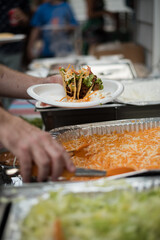Hands getting food from a buffet line
