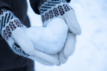 Snowy heart close up in hands. Love symbol for valentine's day and eighth march