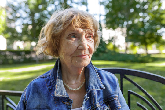 Close-up Portrait Of An Elderly Woman Having A Rest In An Autumn Park. Casual Wear. Looking Away From The Camera.