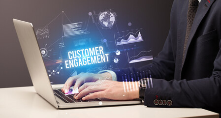 Businessman working on laptop with CUSTOMER ENGAGEMENT inscription, new business concept