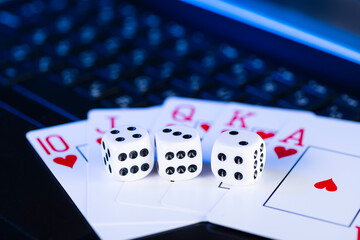 Online gaming platform, casino and gambling business. Cards, dice and multi-colored game pieces on laptop keyboard