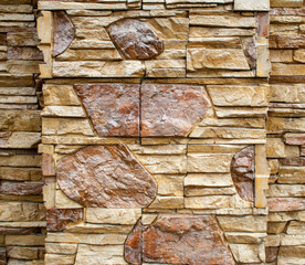 Wall is lined with relief tiles that imitate uneven natural stone. In Mediterranean style - natural colour sandstone. Background square shape. Advertising of building materials, facing tiles