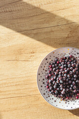 Frozen berries on a plate top view on a wooden background. The concept of a healthy lifestyle, proper nutrition, vegetarianism. Freezing and storing food. Template for the menu. Vertical, copy space.