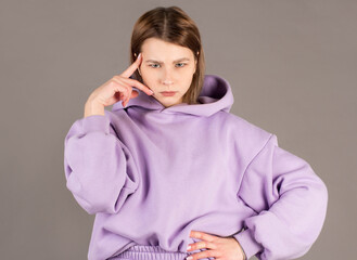 Beautiful female with puzzled expression, keeps finger on head, looks aside with bewilderment,...