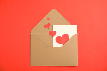 Envelope with card and paper hearts on red background, top view. Love letter