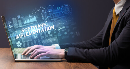 Businessman working on laptop with SOFTWARE IMPLEMENTATION inscription, cyber technology concept