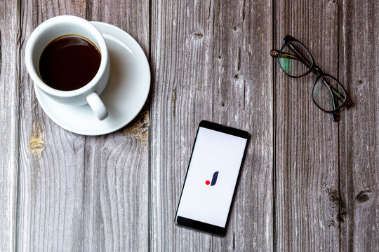 02/10/2021 Portsmouth, Hampshire, UK A mobile phone or cell phone laid on a wooden table with the joom app open on screen next to a coffee
