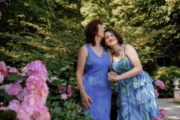 Happy woman have fun in evening gown. Mom and her daughter laughing and walking at the park. Two middle aged women chatting and looking at each other dressed in long dresses.